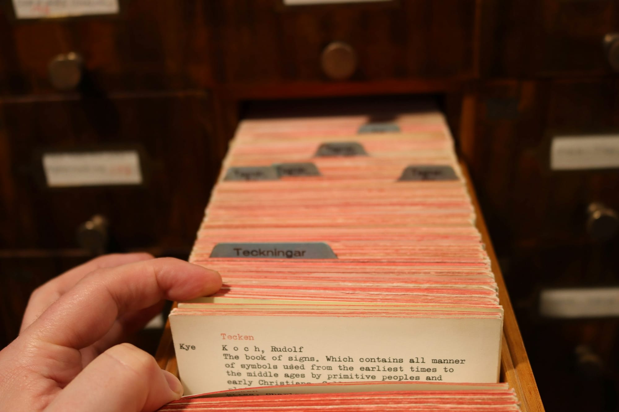A hand pulling a card from a library's card catalogue