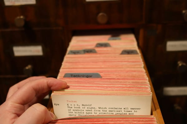 A hand pulling a card from a library's card catalogue